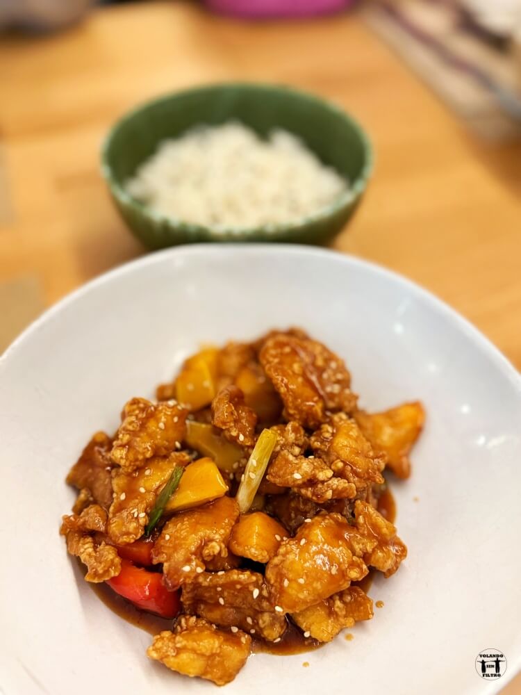 Plato de pollo en trozos con salsa y arroz al fondo