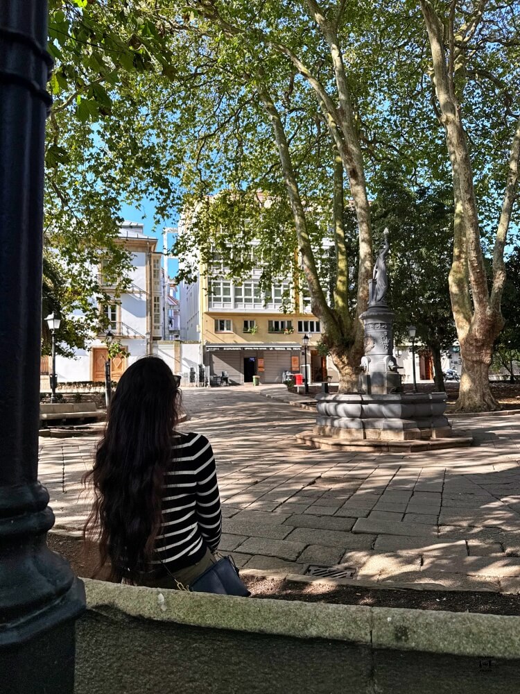 Sandra está de espaldas en primer plano y de fondo la fuente del deseo, punto principal de la plaza 