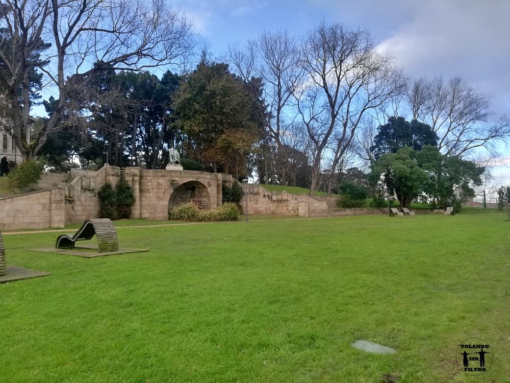 Zona del parque de San Margarita, se ve una zona de césped grande con una arboleda al fondo y unas escaleras de piedra