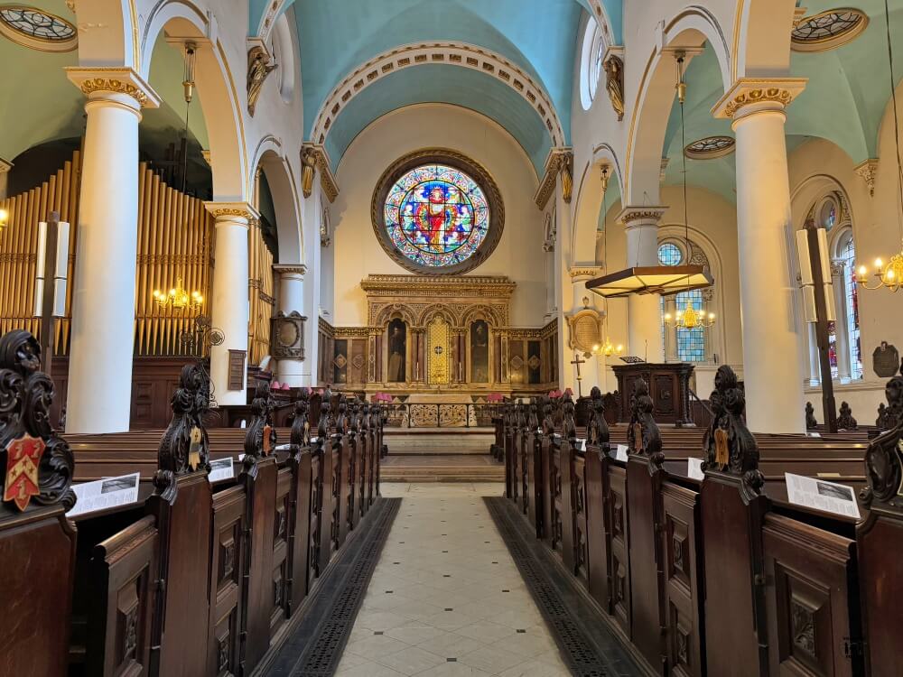 Interior de la iglesia en tonos amarillos y azules con una rosaleda al fondo 