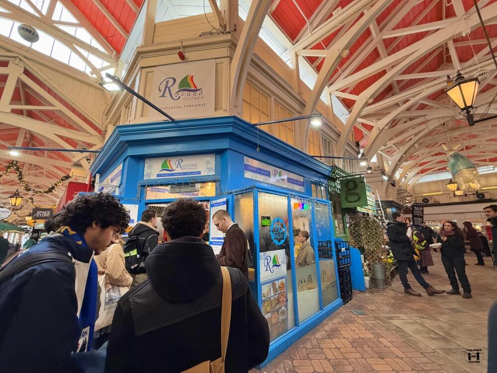Se ve la esquina del restaurante con la cola de gente delante 