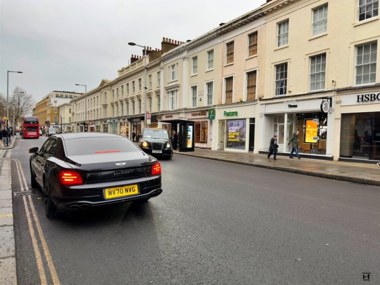 Calle principal de Chelsea con un coche en primer plano y los edificios y un autobús rojo detrás 