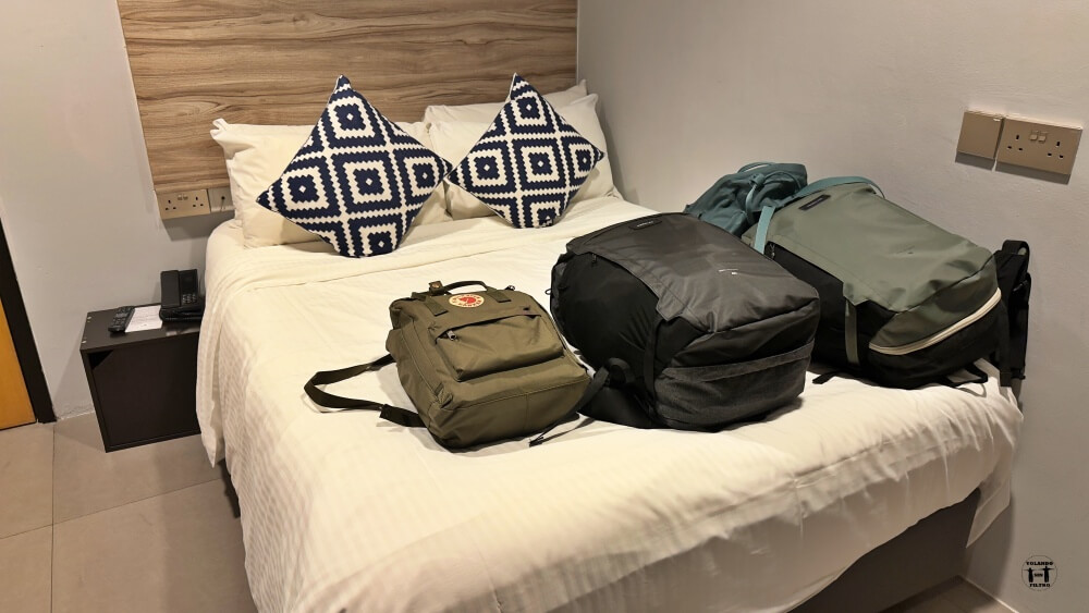 Imagen de la cama con las mochilas encima 