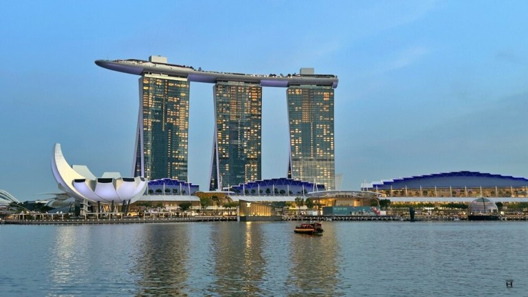 Imagen del hotel Marina Bay Sands con la bahía iluminada en la hora azul. 
