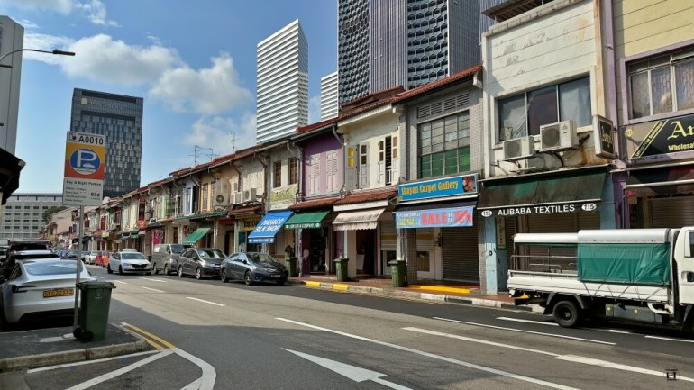 Foto de calle vacía con casas de colores al fondo. 