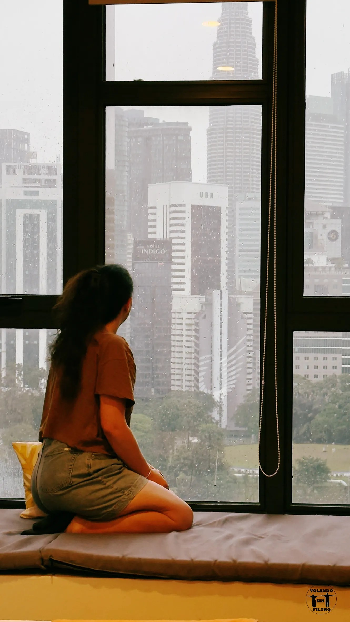 Sandra delante de la ventana mirando las vistas de Kuala Lumpur