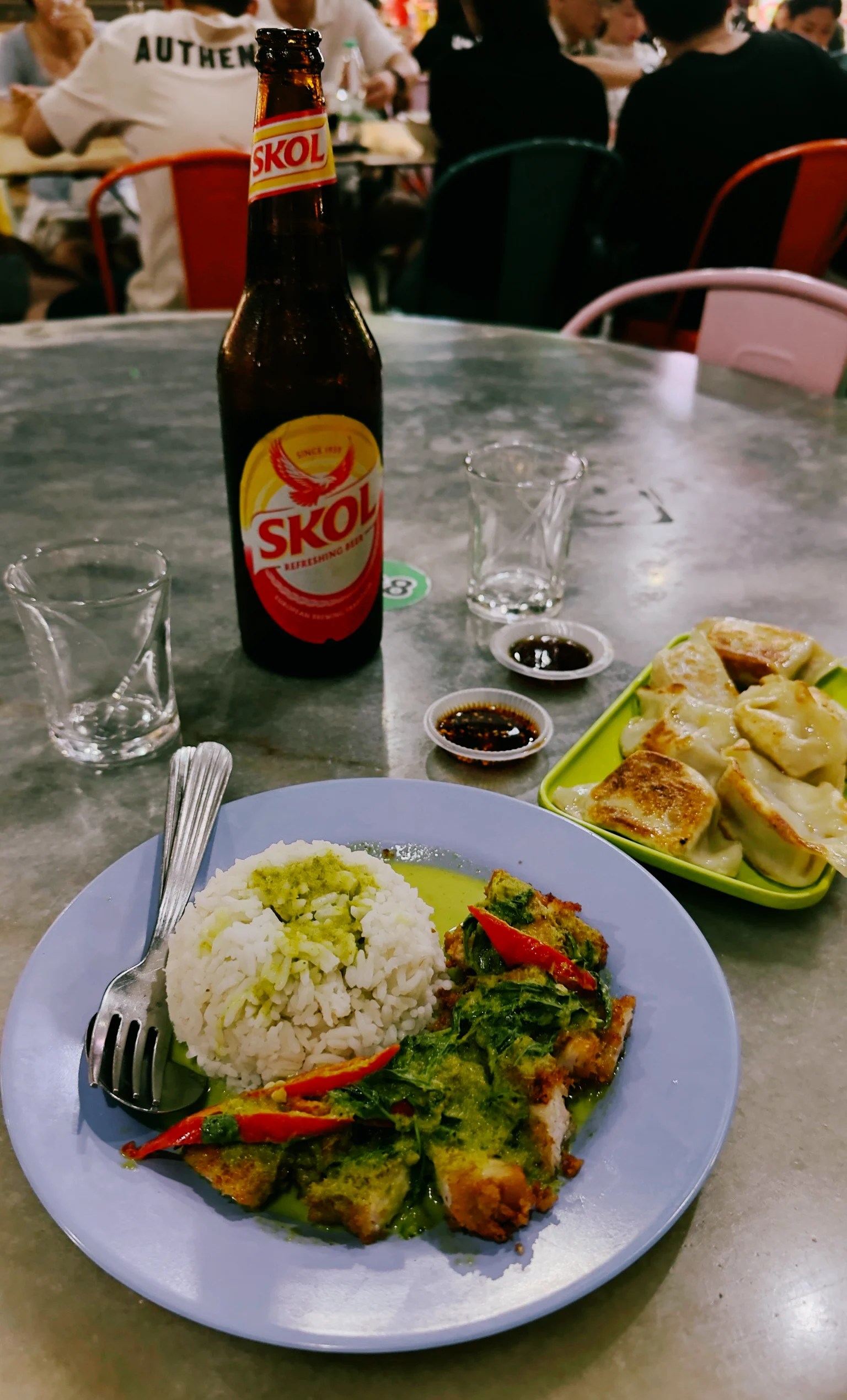 Cerveza de fondo en la mesa y plato de curry al lado de plato de gyozas