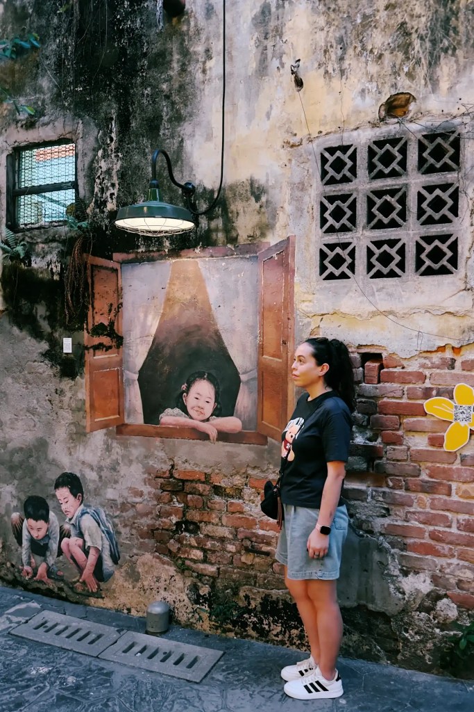 Sandra delante de un mural con niños jugando y asomándose a una ventana