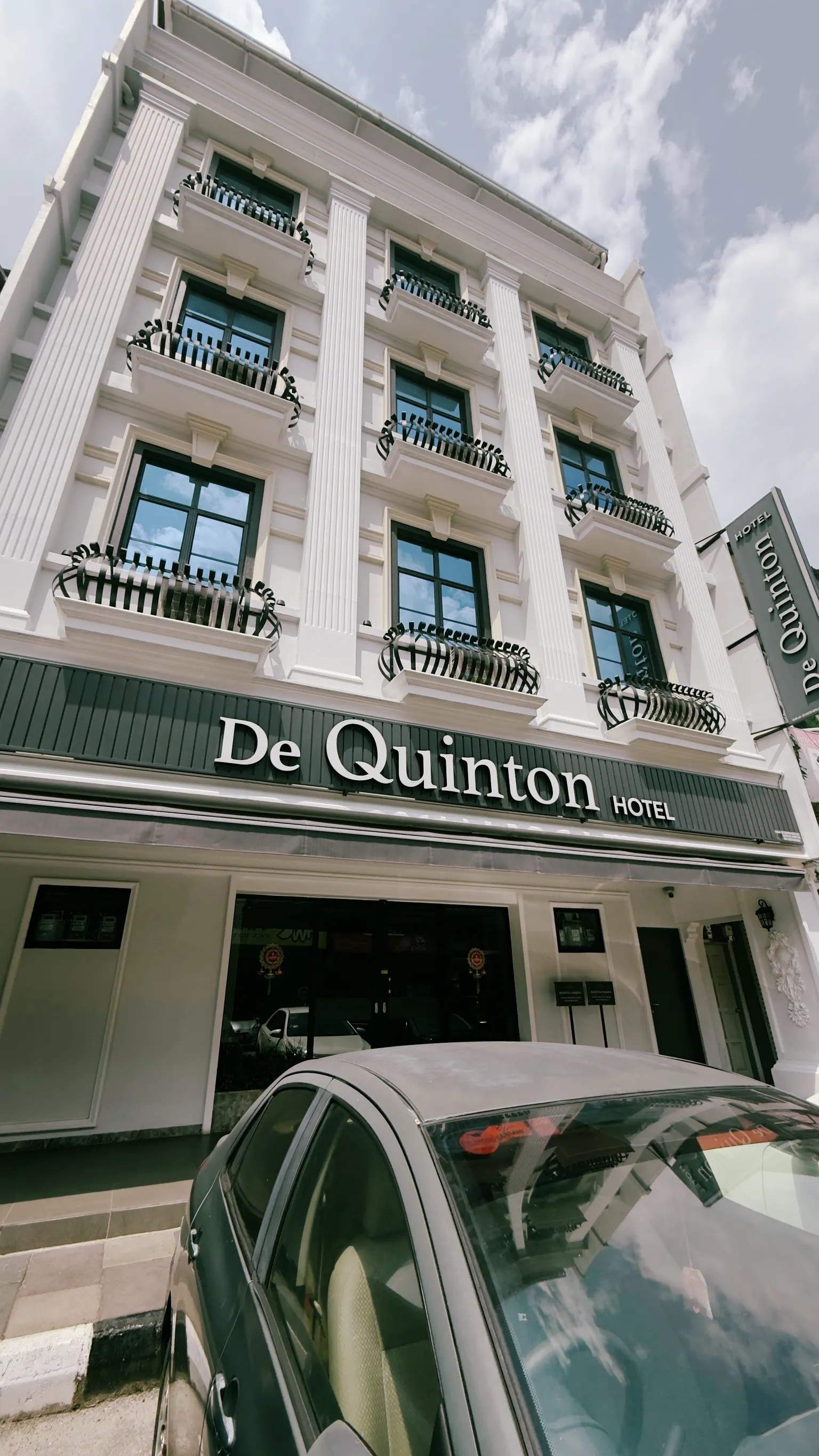 Fachada del hotel de día con un coche delante
