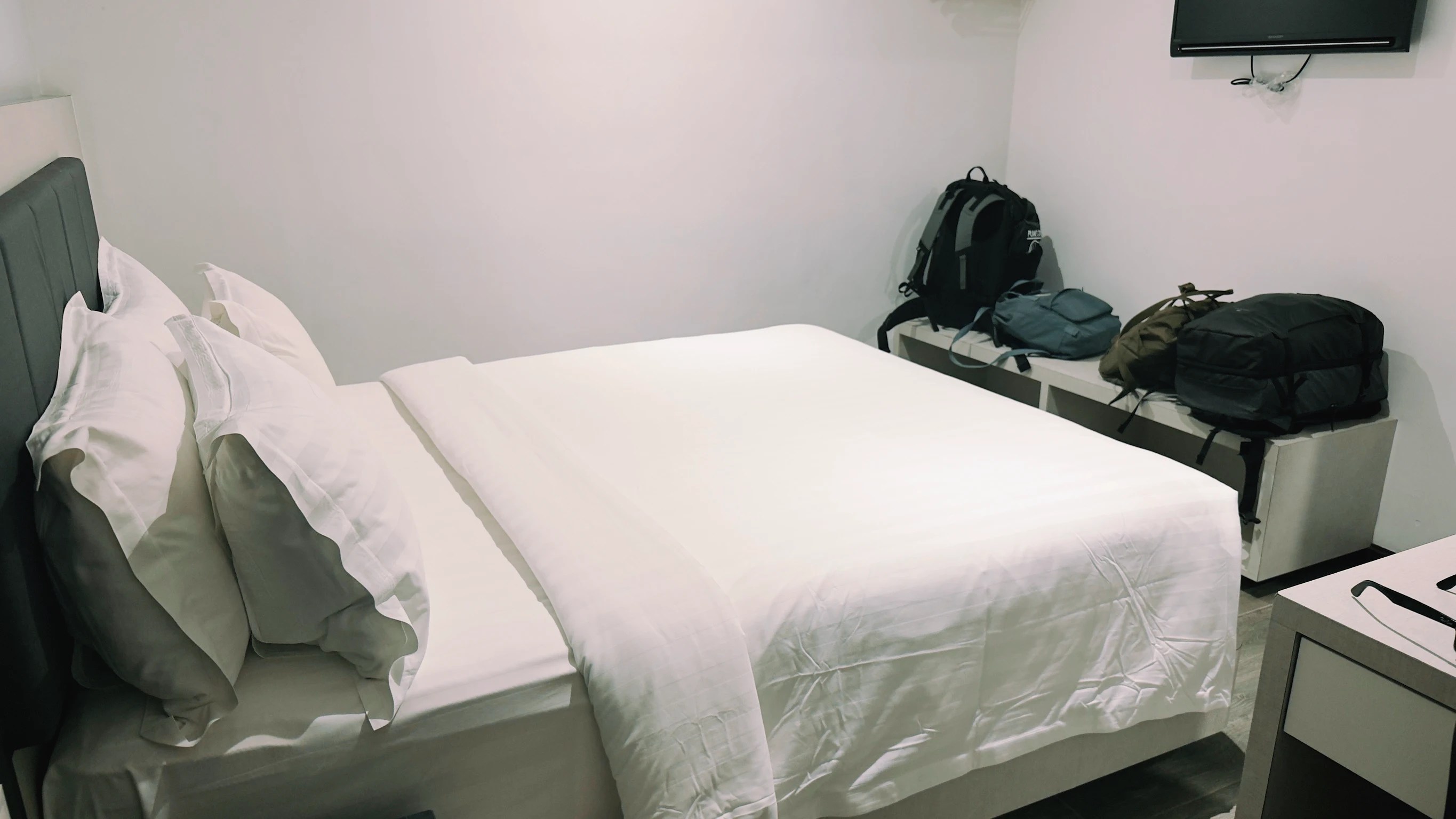 Habitación del hotel, cama en primer plano con mochilas al fondo