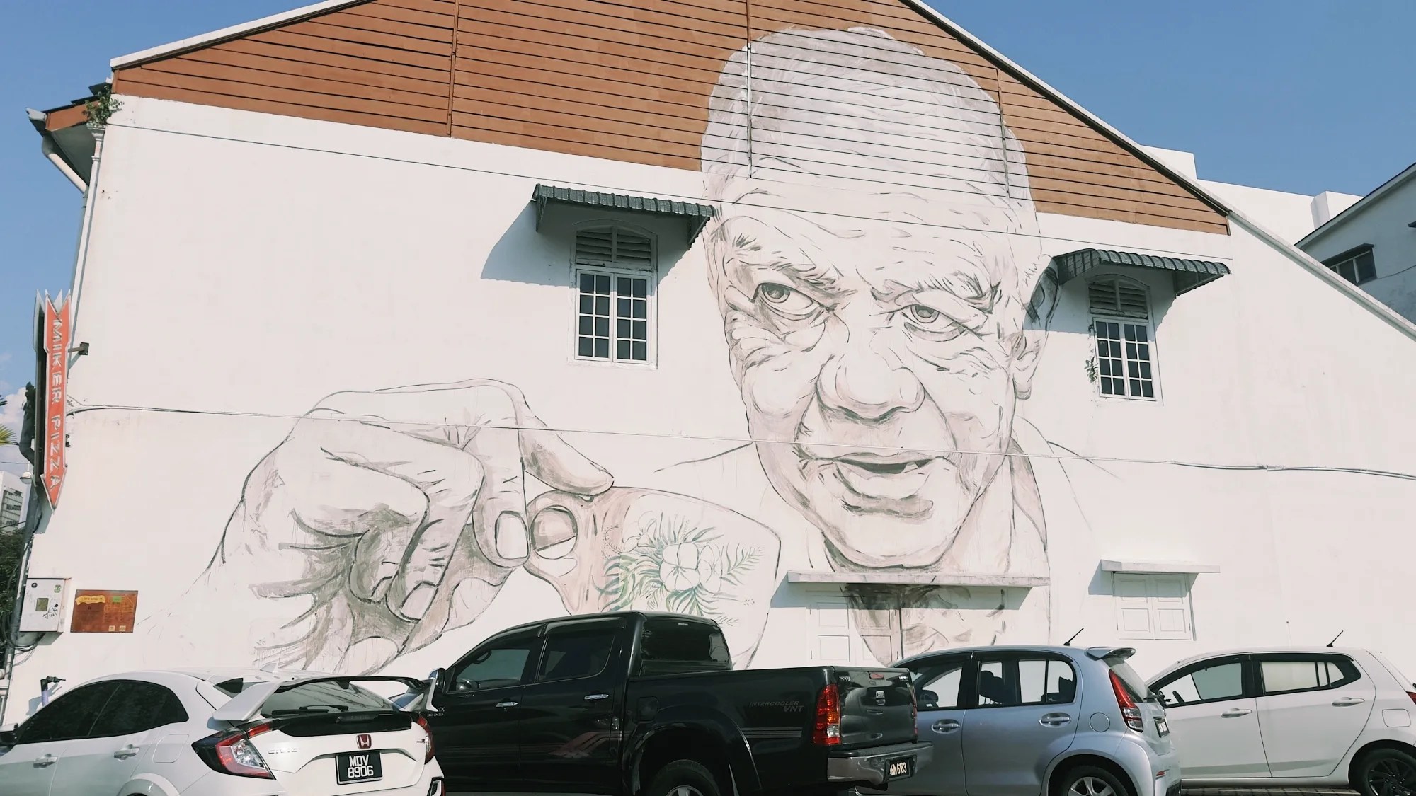 Grafitti en lateral de edificio de un señor con una taza de té en la mano