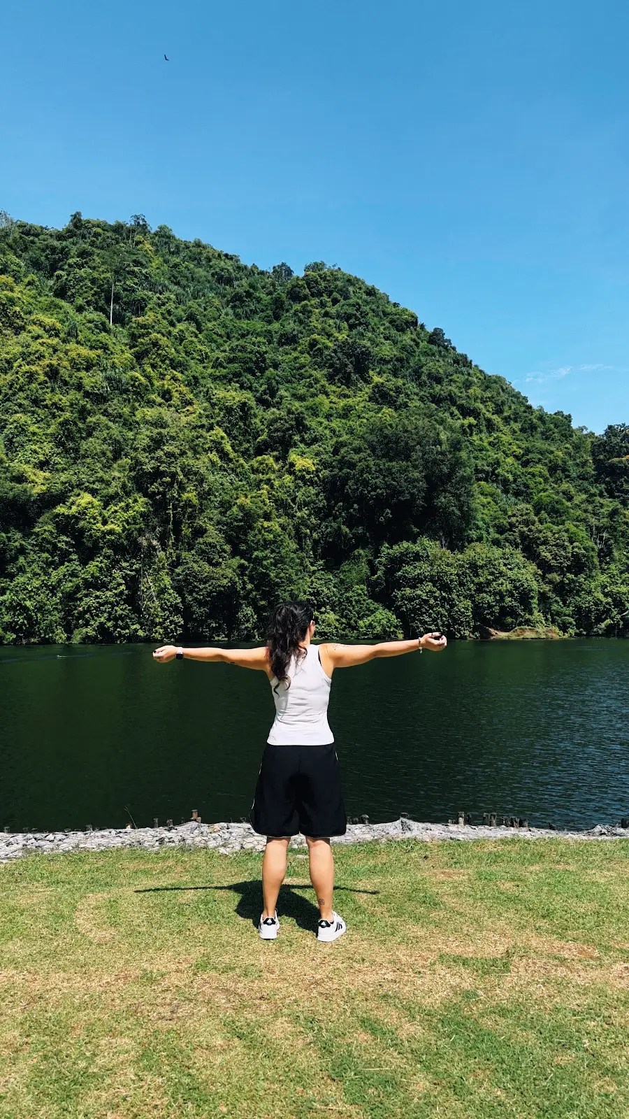 Sandra de espaldas abriendo los brazos con lago en el fondo