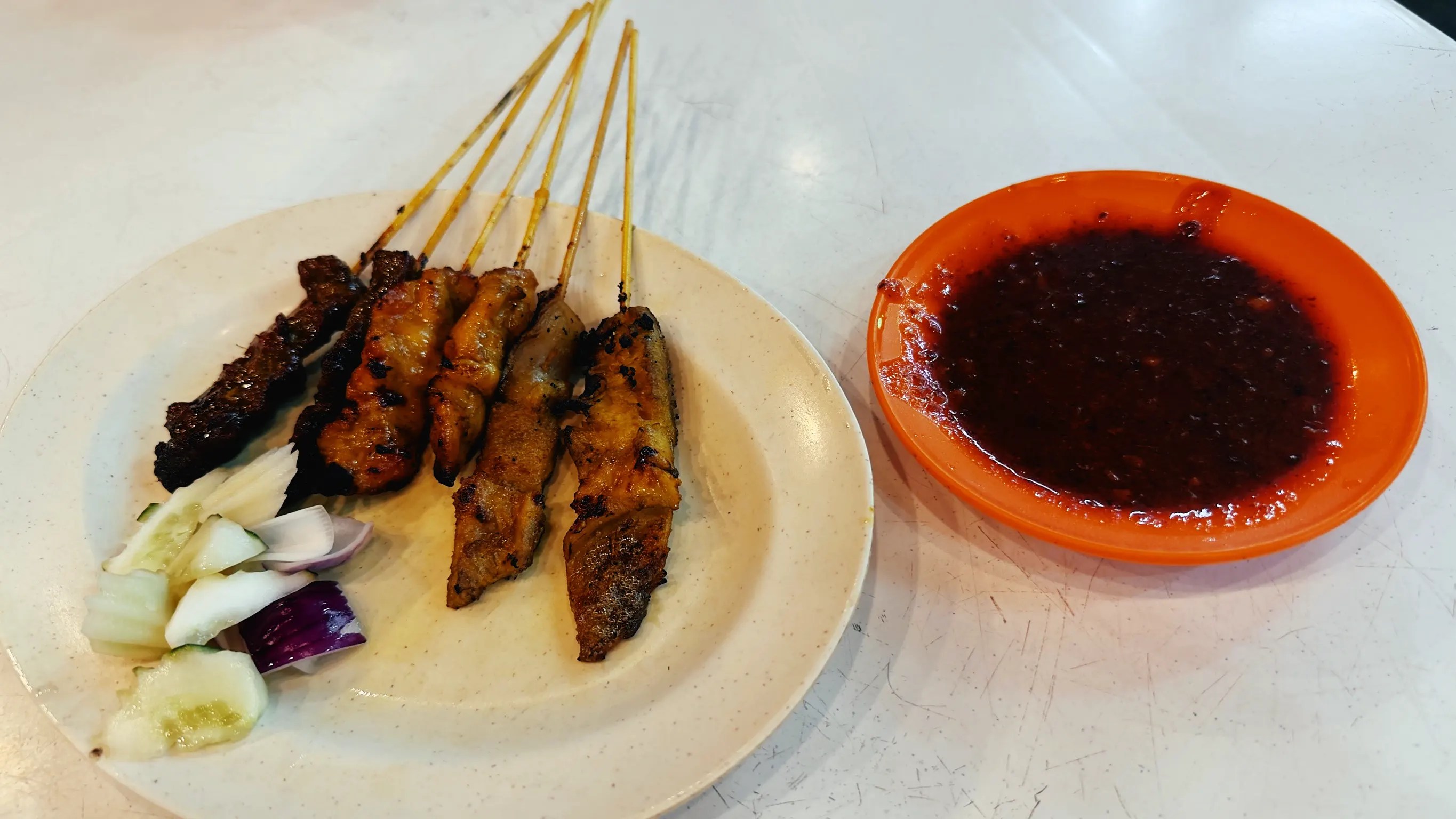 Plato de brochetas con plato al lado de salsa 
